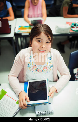 Portrait smiling, confident junior high school girl student using digital tablet in classroom Stock Photo
