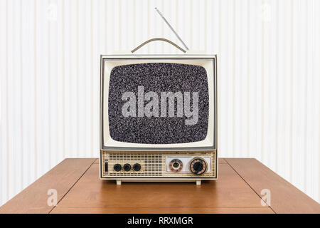 Vintage portable television with static screen and old wood table. Stock Photo