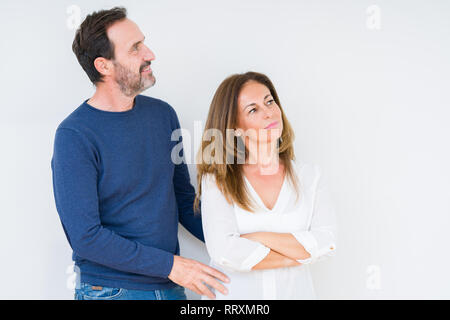 Beautiful middle age couple in love over isolated background smiling looking to the side with arms crossed convinced and confident Stock Photo