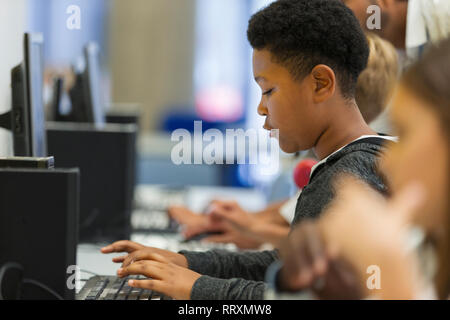 Focused junior high boy student using computer in computer lab Stock Photo