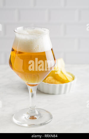 Glass of beer and chips on light background Stock Photo