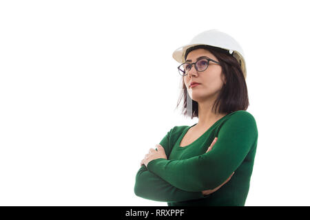 Confident young woman engineer hands crossed wearing protective hardhat and glasses looking away isolated over white background with copy space. Stock Photo