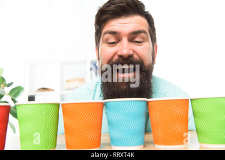 Alternative concept. Pick one. Diversity and recycling. Eco paper cup. Coffee to go paper cup. How many cups per day. Choose from alternatives. Man bearded choosing one of lot colorful paper cups. Stock Photo