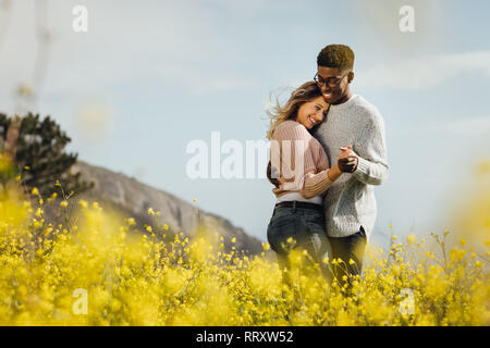 Happy couple dancing together outdoors. African man and caucasian woman enjoying a quality time together. Stock Photo