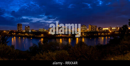 Saskatoon skyline at night along the Saskatchewan River and valley. Saskatchewan is a prairie province in the country of Canada and is rural. Stock Photo