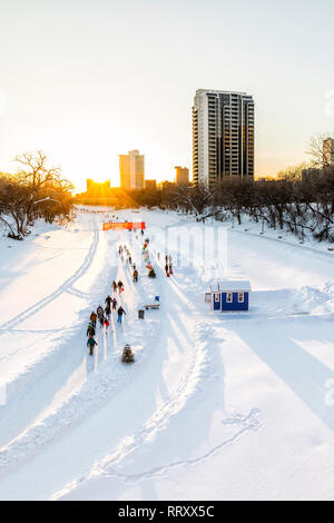 Ice skating on the Assiniboine River Trail at sunset, part of the Red River Mutual Trail, The Forks, Winnipeg, Manitoba, Canada.