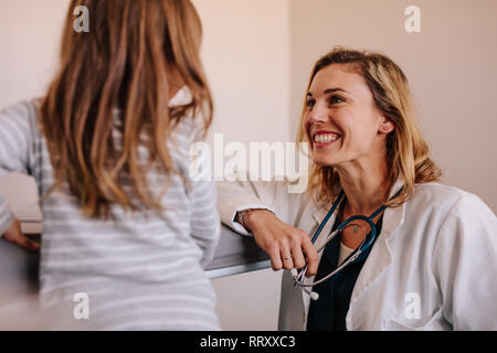 Friendly happy doctor pediatrician with patient child girl in office at clinic. Pediatrician and a girl at hospital. Stock Photo