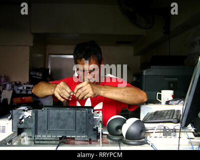 ANTIPOLO CITY, PHILIPPINES - FEBRUARY 21, 2019: A technician at an electrical repair shop fixes a computer printer for a customer. Stock Photo