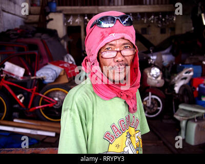 ANTIPOLO CITY, PHILIPPINES - FEBRUARY 21, 2019: A carpenter wearing a shirt on his head as protective gear poses for the camera. Stock Photo