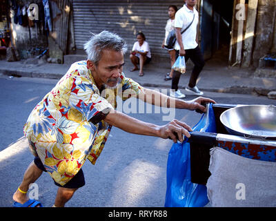 ANTIPOLO CITY, PHILIPPINES - FEBRUARY 21, 2019: A street food vendor pushes his food cart along a busy street. Stock Photo