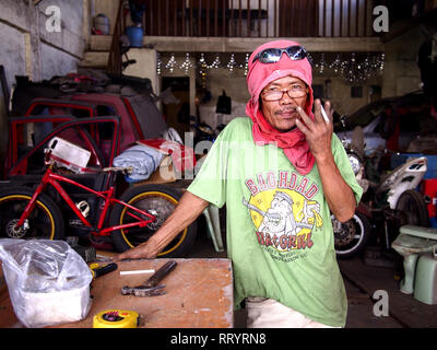 ANTIPOLO CITY, PHILIPPINES - FEBRUARY 21, 2019: A carpenter wearing a shirt on his head as protective gear poses for the camera. Stock Photo