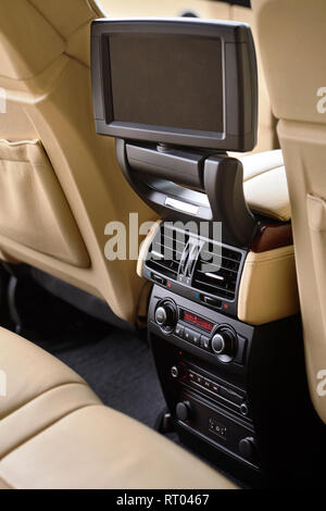 Car inside. Interior in cream colors leather of prestige luxury modern car. Swivel display for back seats passenger with media control panel vertical  Stock Photo