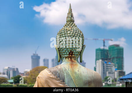 A Buddhist statue at the Seema Malaka Temple on Lake Beira sits against a background of urban development in the Sri Lankan capital of Colombo. Stock Photo