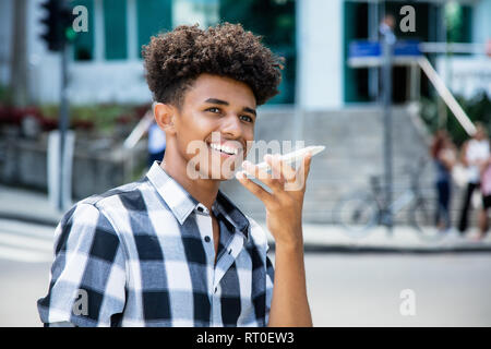 African american young adult using voice recognition at phone outdoor in the city Stock Photo