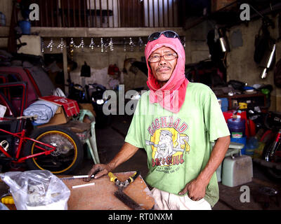 ANTIPOLO CITY, PHILIPPINES - FEBRUARY 21, 2019: A carpenter wearing a shirt on his head as protective gear poses for the camera. Stock Photo