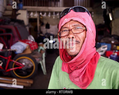 ANTIPOLO CITY, PHILIPPINES - FEBRUARY 21, 2019: A carpenter wearing a shirt on his head as protective gear poses for the camera. Stock Photo