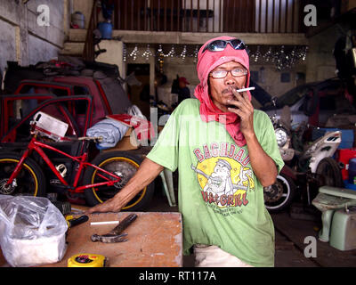 ANTIPOLO CITY, PHILIPPINES - FEBRUARY 21, 2019: A carpenter wearing a shirt on his head as protective gear poses for the camera. Stock Photo