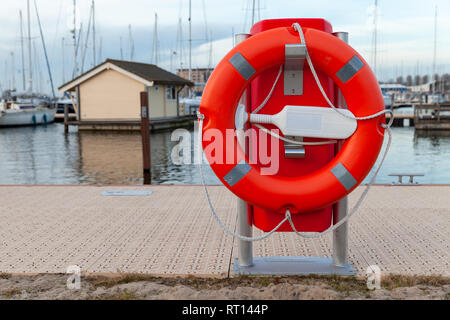 Red lifebuoy placed on a lake coast in Netherlands Stock Photo