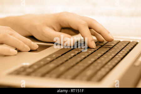 Female hands on laptop keyboard. Picture in sepia tint. Stock Photo