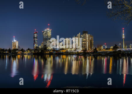 Vienna, Austria - December 29, 2017. Evening view of Donau City or Vienna DC with Andromeda Tower and modern architecture buildings reflected in water Stock Photo