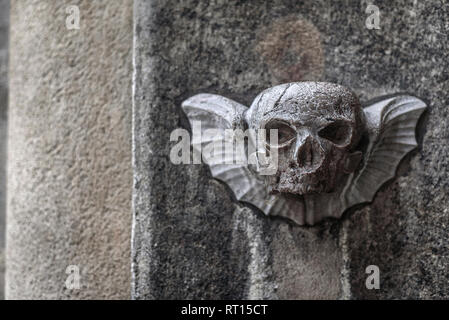 Vienna, Austria - December 30, 2017. Carved stone scull with wings on old church facade wall. Decorative bas-relief sculpture depicts winged mortality Stock Photo