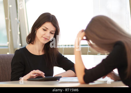 employees using their gadgets, sitting at a table in a cafe. Stock Photo