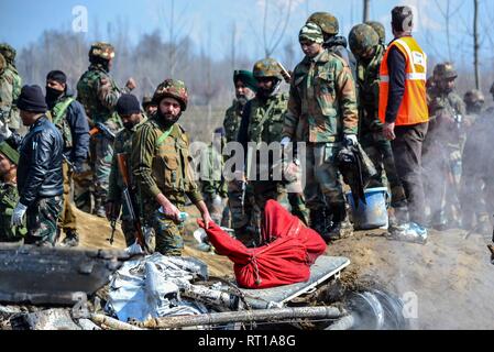 Budgam, Kashmir. 27th February, 2019. An Indian army man stands near the dead body of the pilot after an Indian military aircraft crashed in Budgam, 20kms from Srinagar, Kashmir. An Indian Air Force aircraft crashed on Wednesday in Budgam district of Kashmir, killing seven persons including six Indian Air Force personnel and one civilian. The aircraft crashed due to technical reasons, officials said. Credit: Saqib Majeed/SOPA Images/ZUMA Wire/Alamy Live News Stock Photo