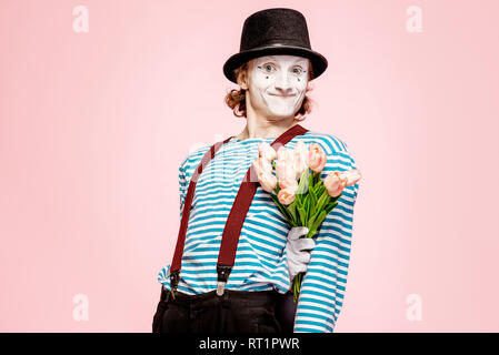 Emotional pantomime posing with tulip bouquet on the pink background indoors. Valentine's Day and love concept Stock Photo