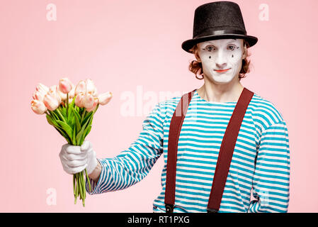 Emotional pantomime posing with tulip bouquet on the pink background indoors. Valentine's Day and love concept Stock Photo