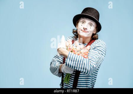 Emotional pantomime posing with tulip bouquet on the blue background indoors. Valentine's Day and love concept Stock Photo