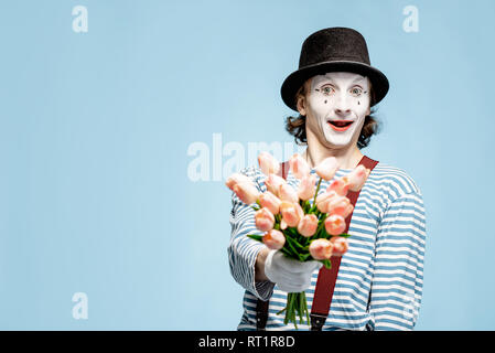Emotional pantomime posing with tulip bouquet on the blue background indoors. Valentine's Day and love concept Stock Photo