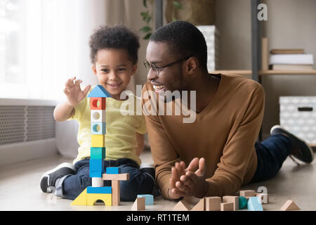Happy little son playing with black dad using wooden blocks Stock Photo