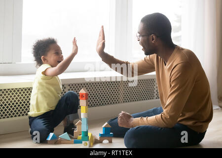 Happy black dad and toddler son giving high-five playing together Stock Photo