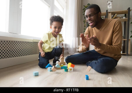 Happy joyful african dad and toddler son laughing playing together Stock Photo