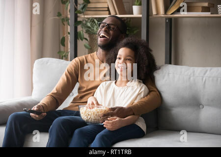 Cheerful african american father and child girl laughing watching tv Stock Photo