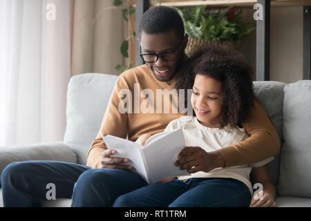 Happy family black father and kid daughter reading story book Stock Photo