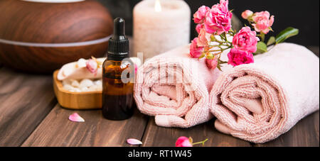 Fresh bright pink roses, petals, candle, and towel in a spa Stock