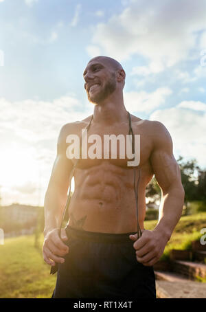 Portrait of smiling barechested muscular man with skipping rope outdoors Stock Photo