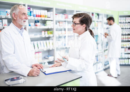 Two pharmacists with clipboard at counter in pharmacy Stock Photo