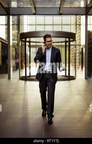 Businessman on cell phone in foyer of an office building Stock Photo