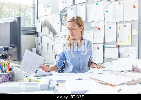 Woman sitting at desk in office doing paperwork Stock Photo