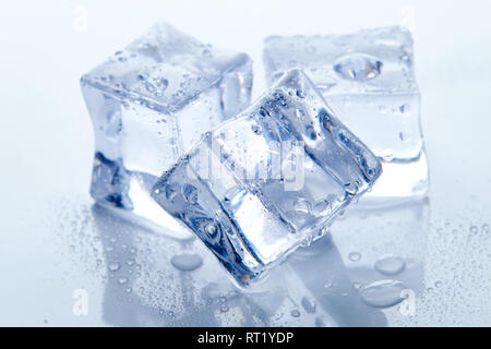 Wet square ice cubes on reflective light blue background Stock Photo