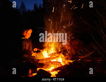 Argentina, Patagonia, Lago Futalaufquen, boy at camp fire at night Stock Photo