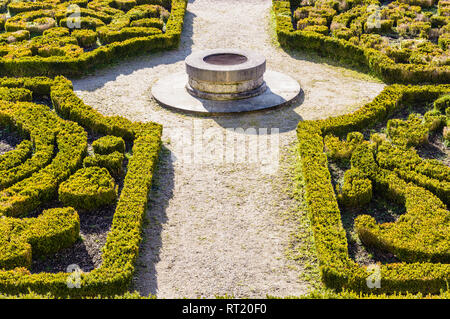 The parterre de broderie in the french formal garden of the castle of Auvers-sur-Oise with beds of boxwood pruned in geometrical shapes around a well. Stock Photo