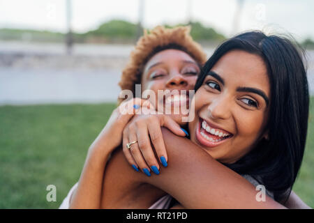 Portrait of two happy female friends hugging in a park Stock Photo