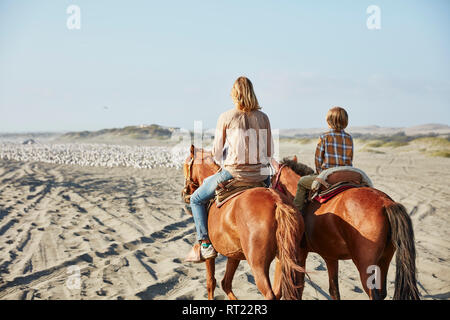 Chile, Vina del Mar, mother with son riding horses on the beach Stock Photo