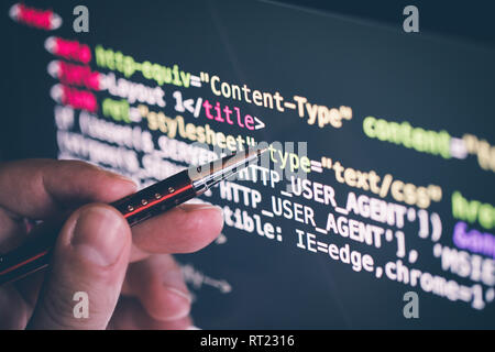 pointing on software code at the computer screen with pen, closeup Stock Photo