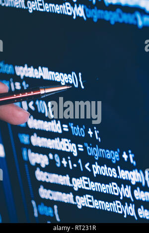 pointing on software code at the computer screen with pen, closeup Stock Photo