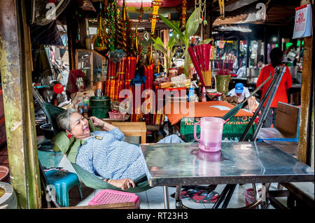 A Cambodian fortune teller relaxes at her stall waiting for a customer in a busy Phnom Penh indoor market. Phnom Penh Cambodia. Stock Photo