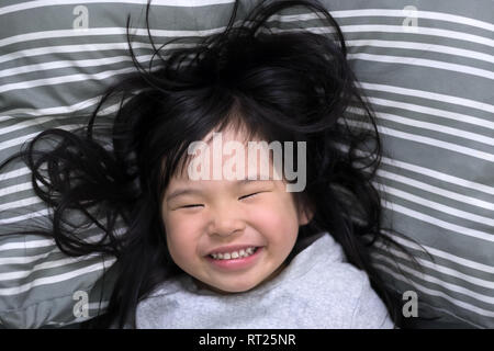 Young girl wakes up in the morning smiling Stock Photo